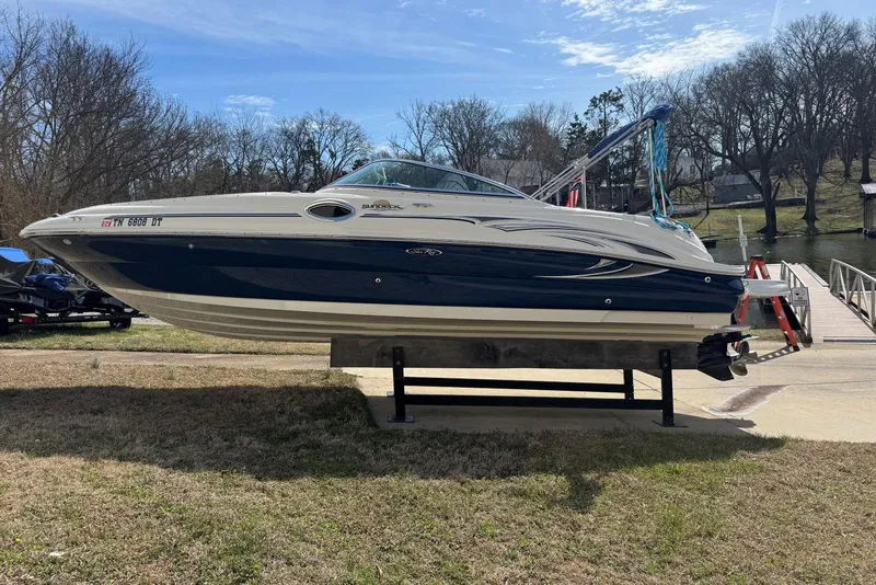 Slide: The Image of 2006 Sea Ray 240 Sundeck boat on display near a dock, clear sky background. - 7