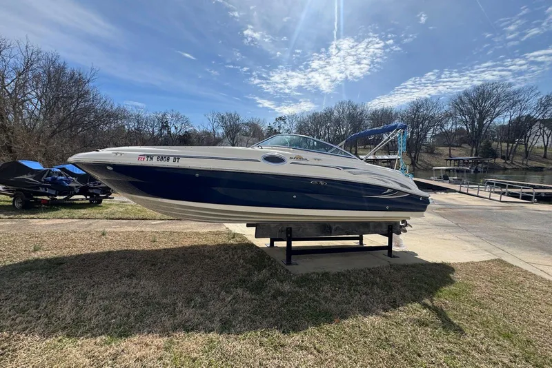 Slide: The Image of 2006 Sea Ray 240 Sundeck boat on display, sunny day, near a lake. - 8