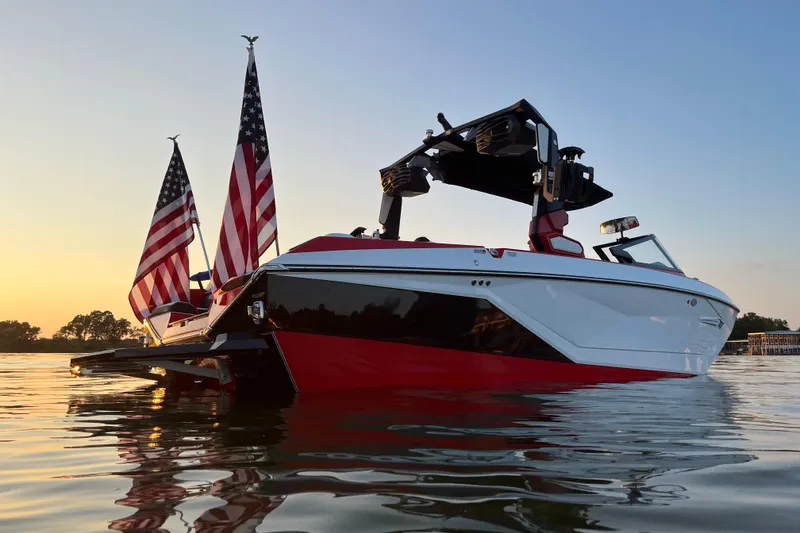 Slide: The Image of 2023 Nautique Super Air Nautique G23 boat with American flags at sunset on the water. - 9