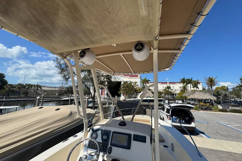 Slide: The Image of 2023 Scout 195 Sportfish boat with canopy, docked near waterfront, clear sky. - 12