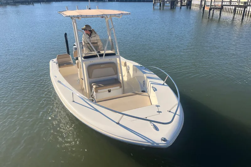Slide: The Image of 2023 Scout 195 Sportfish boat on calm water, featuring a sleek design and spacious deck. - 4