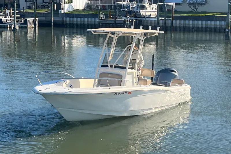 Slide: The Image of 2023 Scout 195 Sportfish boat cruising on calm water near docks. - 8