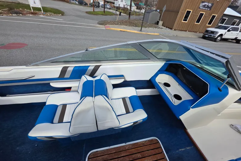 Slide: The Image of 1990 Sea Ray 210 Bow Rider interior with blue and white seating, cup holders, and windshield. - 13