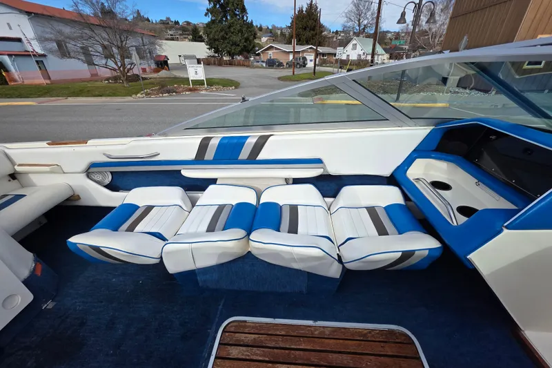 Slide: The Image of 1990 Sea Ray 210 Bow Rider interior with blue and white seating, parked on a street. - 14