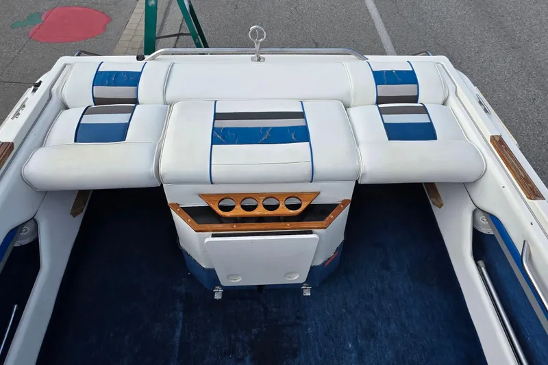 Slide: The Image of 1990 Sea Ray 210 Bow Rider interior with white and blue seating, wood accents. - 16