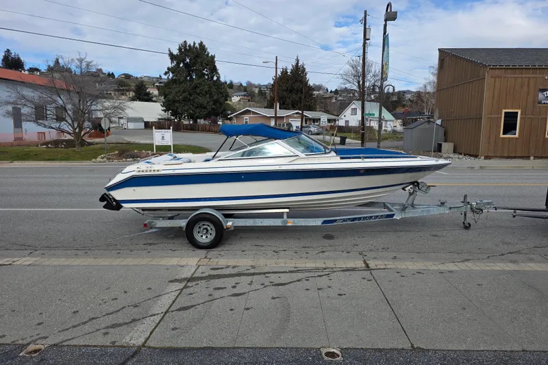 Slide: The Image of 1990 Sea Ray 210 Bow Rider boat on trailer, parked on a street. - 2