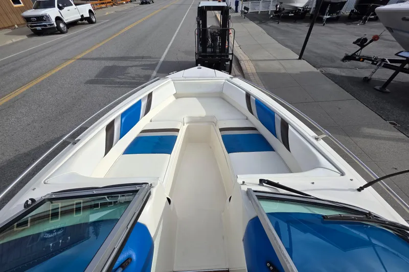 Slide: The Image of 1990 Sea Ray 210 Bow Rider with blue and white seating, parked on a street. - 6