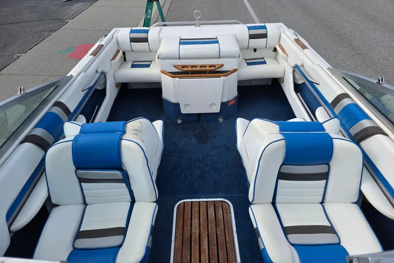 Slide: The Image of 1990 Sea Ray 210 Bow Rider interior with blue and white seating, wooden accents. - 8