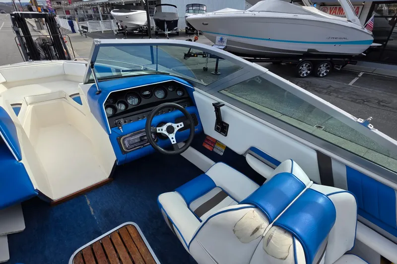 Slide: The Image of 1990 Sea Ray 210 Bow Rider interior with blue and white seating, dashboard, and steering wheel. - 9