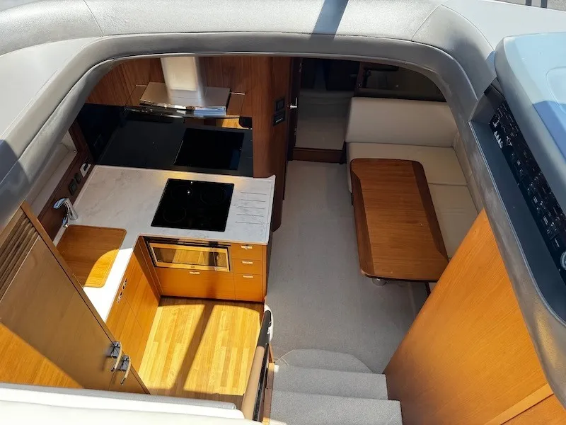 Slide: The Image of Interior view of a modern yacht with kitchen, dining table, and seating area, all in wood finish. - 26