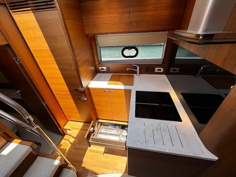 Slide: The Image of The yacht's kitchen features wooden cabinets, a stove, and a sink. A window offers an outside view. - 28