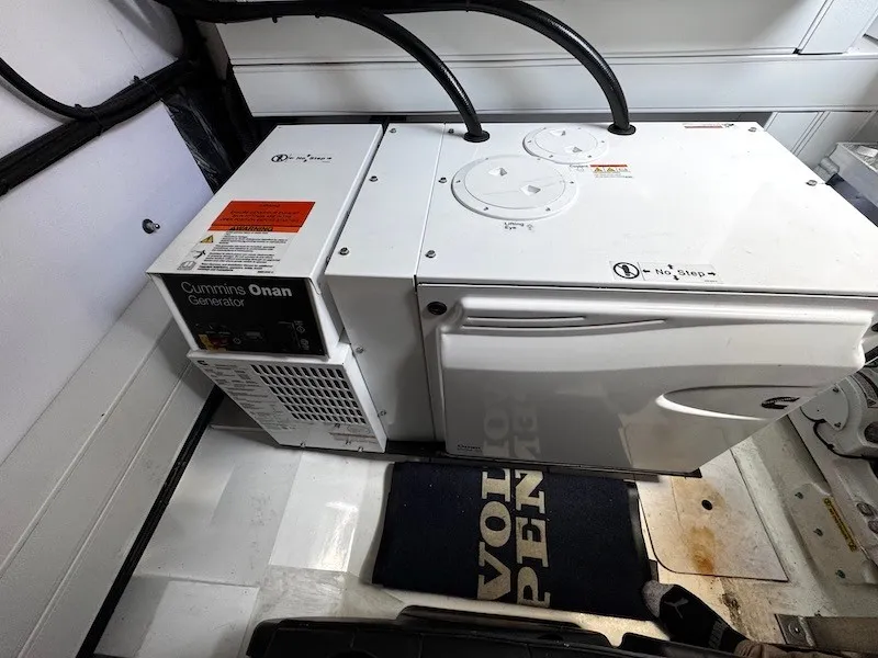 Slide: The Image of A Cummins Onan generator in a boat engine room, surrounded by white panels and cables. - 49