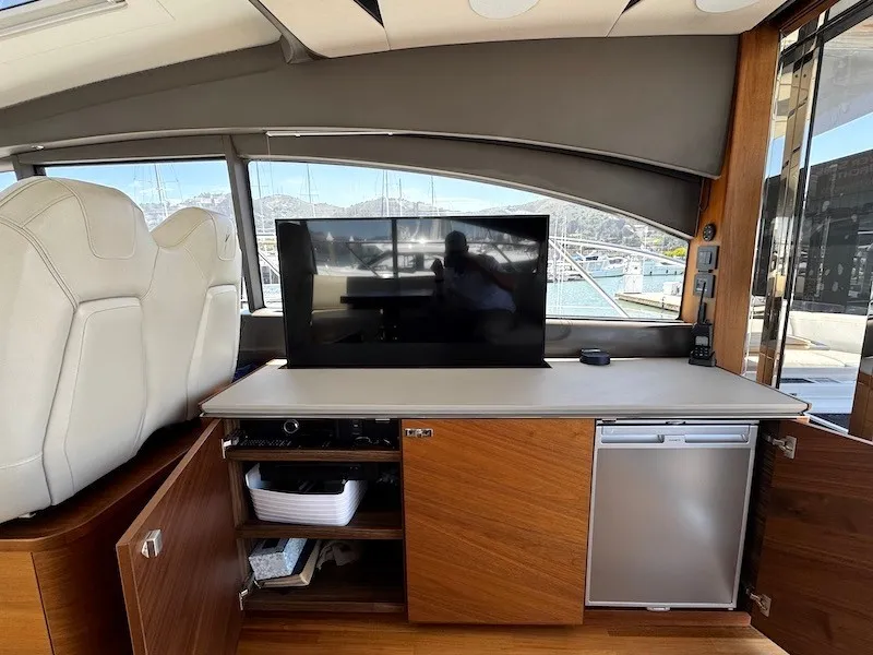 Slide: The Image of Interior of a 2020 Princess V50 with a TV, refrigerator, and storage space. - 19