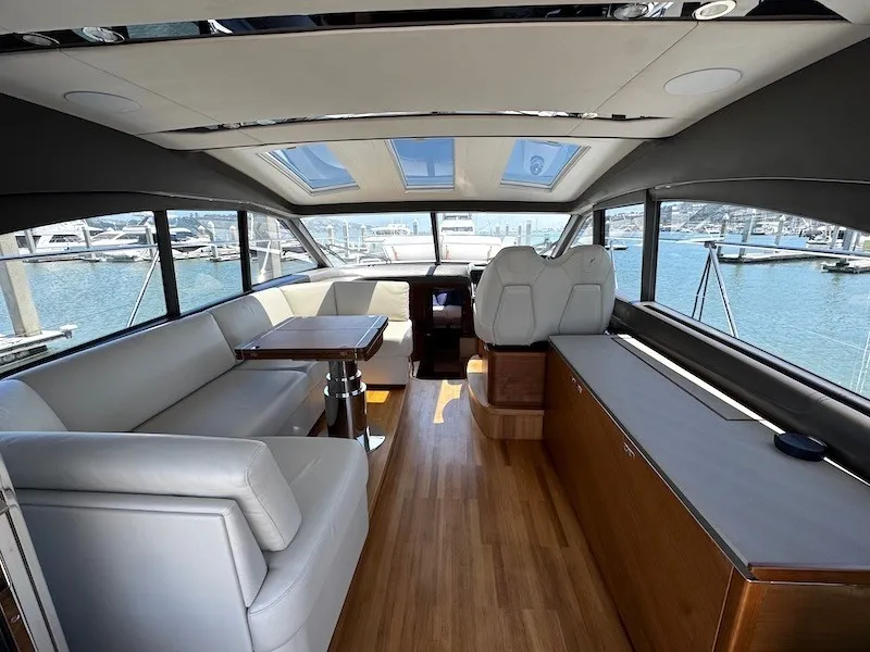 Slide: The Image of Interior of a luxury yacht with wooden flooring, white leather seating, and large windows overlooking the marina. - 15