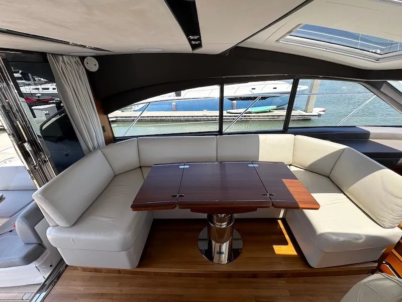 Slide: The Image of Interior view of a luxury yacht with an elegant white seating area and a wooden table. - 16