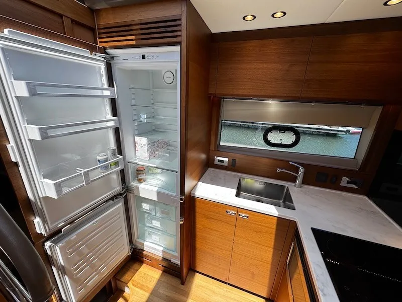 Slide: The Image of The 2020 Princess V50 kitchen features an open fridge, a sink, and a window. - 31