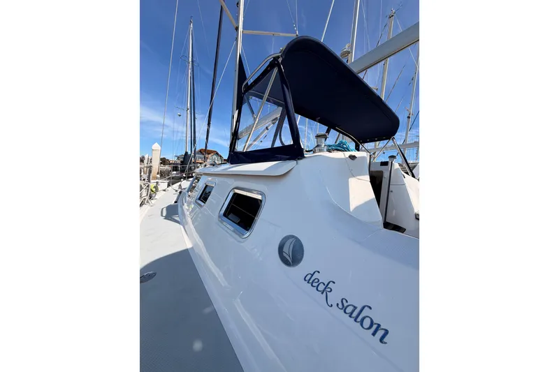 Slide: The Image of 2007 Hunter 44 Deck Salon sailboat with blue canopy, docked under clear sky. - 12
