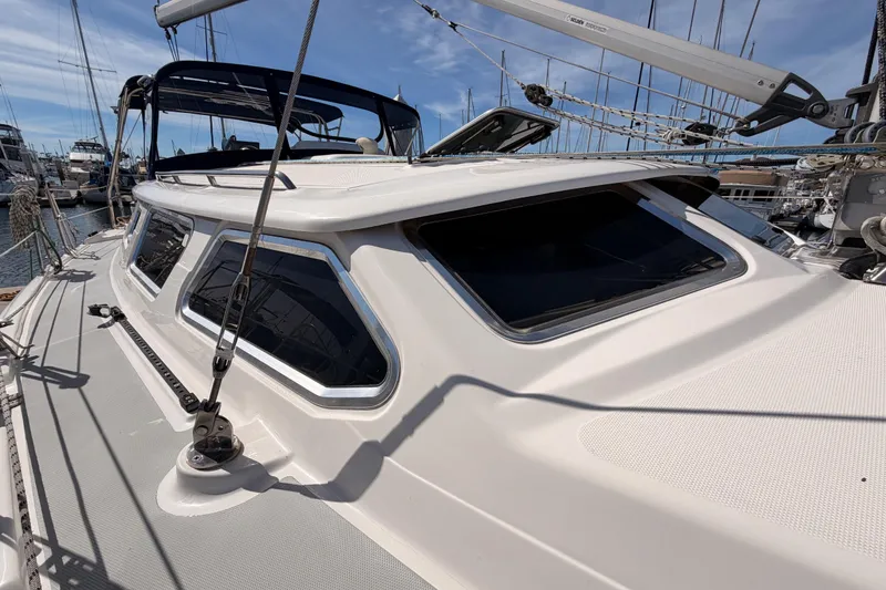 Slide: The Image of 2007 Hunter 44 Deck Salon sailboat with sleek windows, docked in a marina. - 19