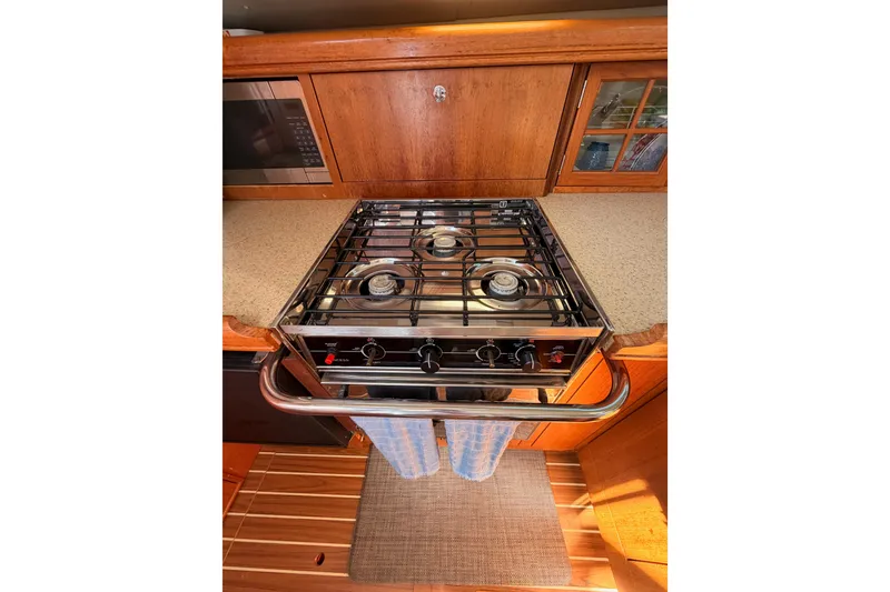Slide: The Image of 2007 Hunter 44 Deck Salon kitchen with stove, microwave, and wooden cabinetry. - 38