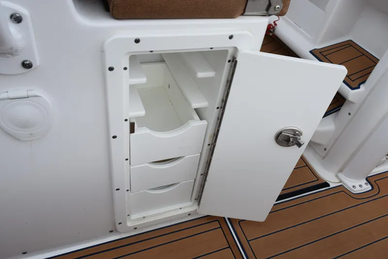 Slide: The Image of Open storage compartment on 2022 Sea Hunt Ultra 275 SE boat with teak flooring. - 22