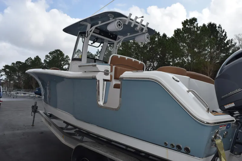 Slide: The Image of 2022 Sea Hunt Ultra 275 SE boat with blue hull and brown seating, parked outdoors. - 6