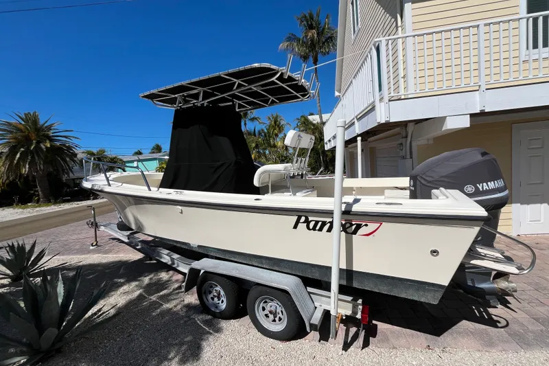 Slide: The Image of 2009 Parker 2300 Special Edition boat on trailer, parked near a house with palm trees. - 4