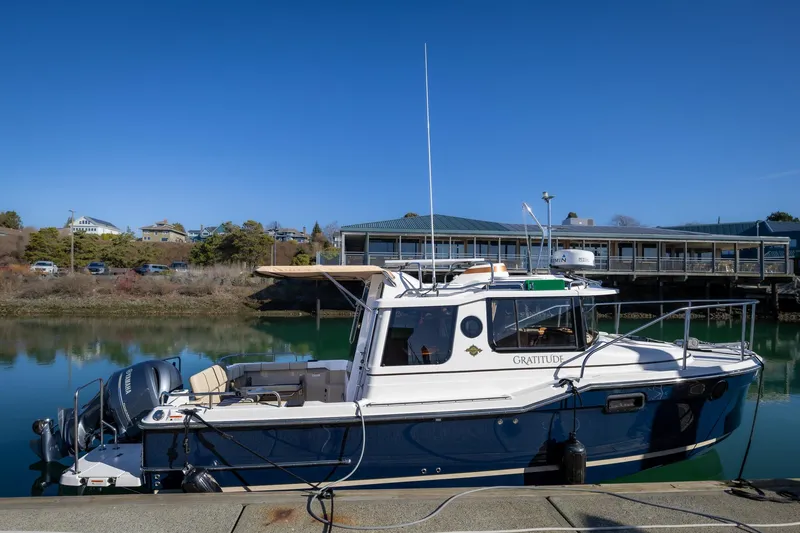The Image of 2019 Ranger Tugs R-23 boat docked by a calm waterfront under clear blue skies. - 0