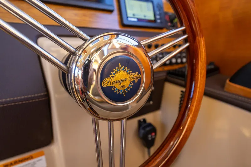 Slide: The Image of Steering wheel of 2019 Ranger Tugs R-23 boat, featuring wood and chrome details. - 11