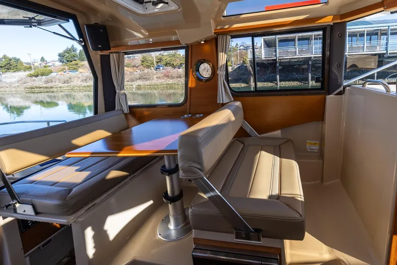 Slide: The Image of 2019 Ranger Tugs R-23 interior with dining area, featuring cushioned seating and wooden table. - 12