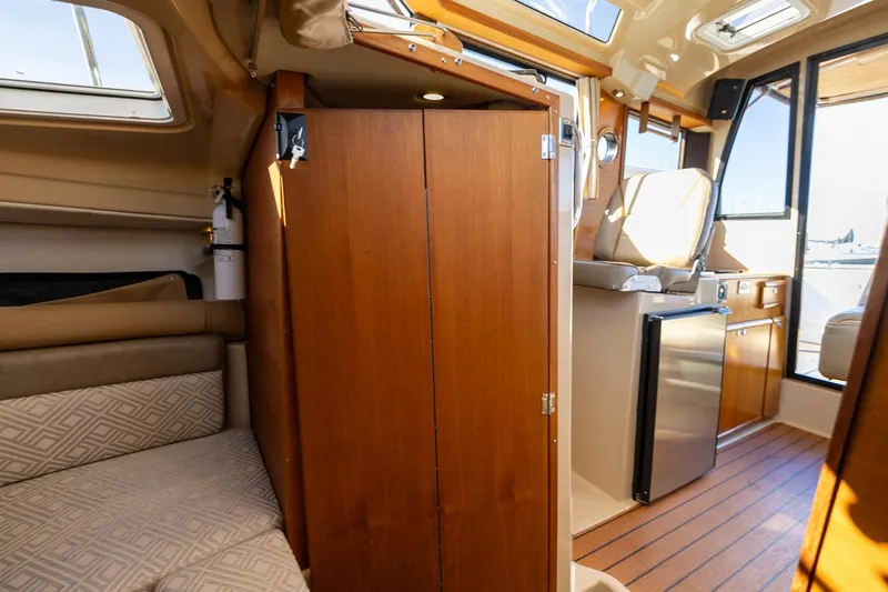 Slide: The Image of 2019 Ranger Tugs R-23 interior with wood cabinetry, seating, and compact kitchen area. - 18