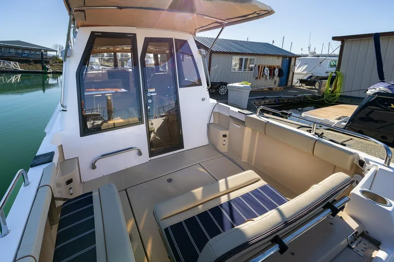 Slide: The Image of 2019 Ranger Tugs R-23 boat with spacious deck and seating at a marina. - 2
