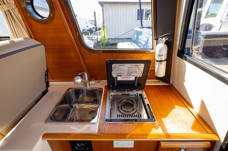 Slide: The Image of 2019 Ranger Tugs R-23 interior galley with sink, stove, and fire extinguisher. - 21