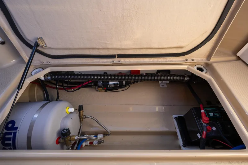 Slide: The Image of 2019 Ranger Tugs R-23 boat compartment with battery and plumbing components. - 23