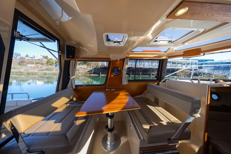 Slide: The Image of 2019 Ranger Tugs R-23 interior with seating and table, featuring large windows and natural light. - 7