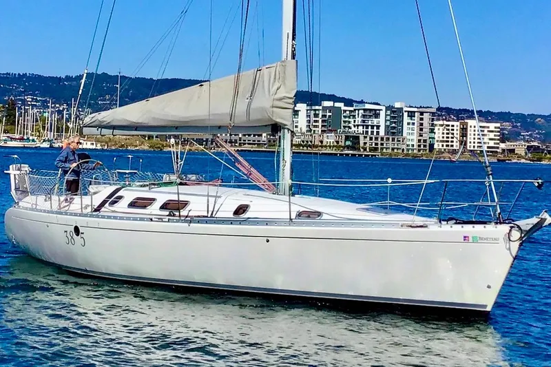 The Image of 1991 Beneteau First 38s5 sailboat on water, with cityscape background. - 0