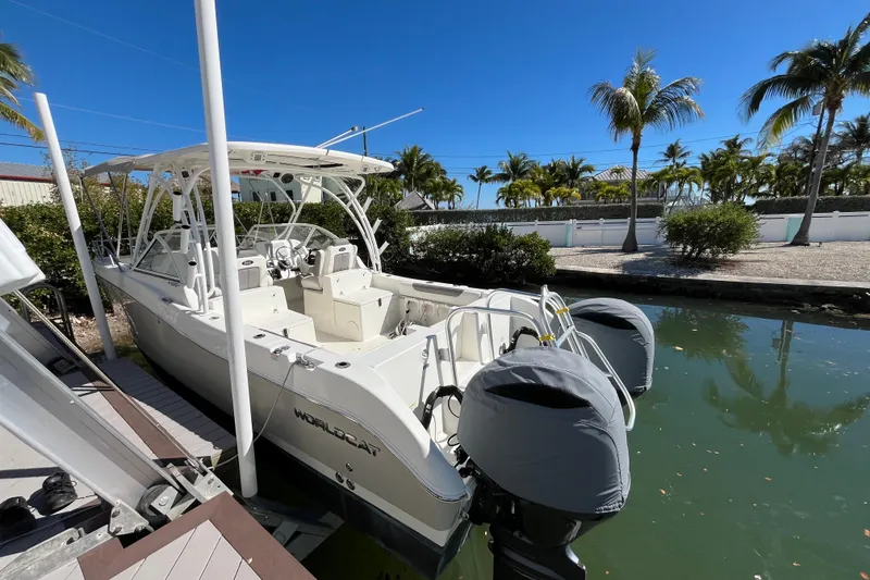 Slide: The Image of 2017 World Cat 255 DC boat docked by palm trees under clear blue sky. - 1