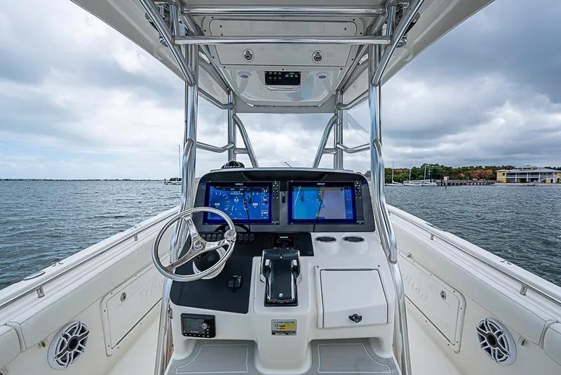 Slide: The Image of 2007 Triton 351 CC boat helm with dual screens, steering wheel, and ocean view. - 16