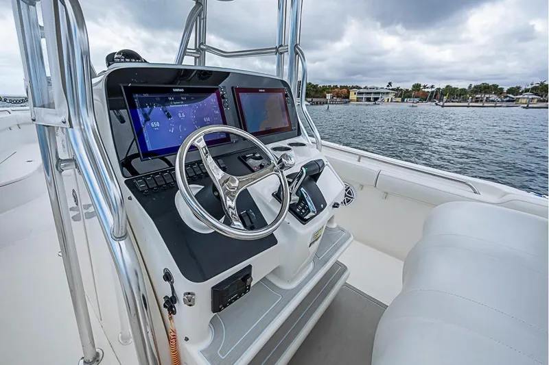 Slide: The Image of 2007 Triton 351 CC boat helm with modern navigation displays and steering wheel, dockside view. - 17