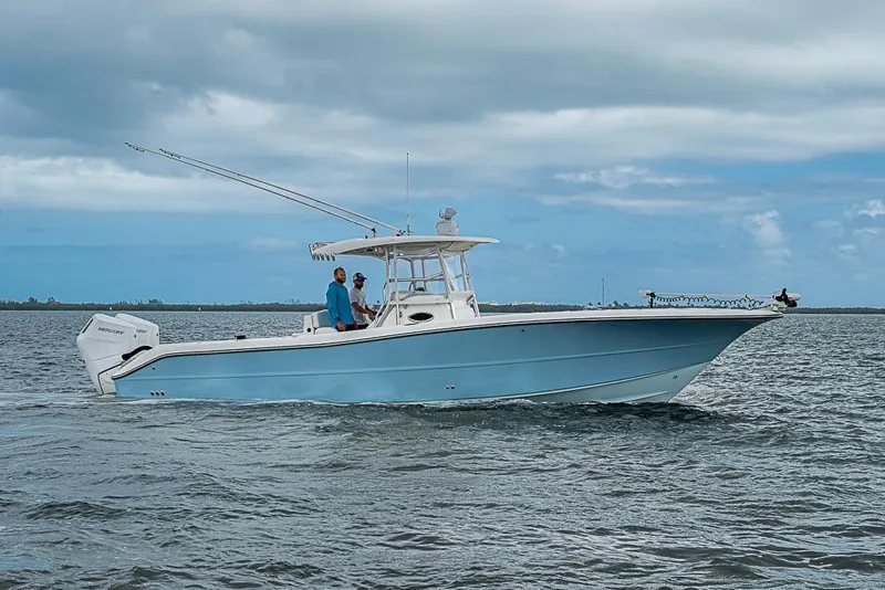 Slide: The Image of 2007 Triton 351 CC boat cruising on open water under cloudy skies. - 2