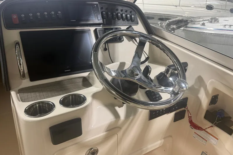 Slide: The Image of 2022 Grady-White Freedom 307 boat dashboard with steering wheel and control panel. - 29