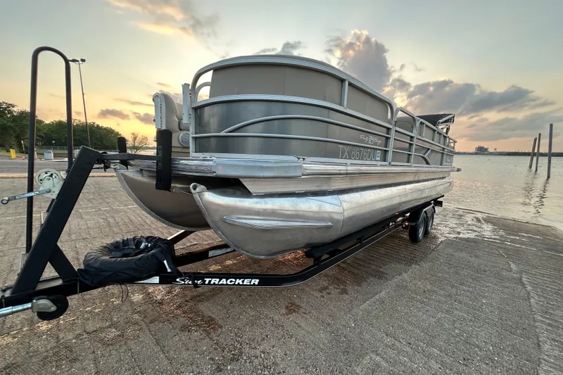 Slide: The Image of 2017 Sun Tracker Party Barge 24 DLX on trailer at sunset by the water. - 67