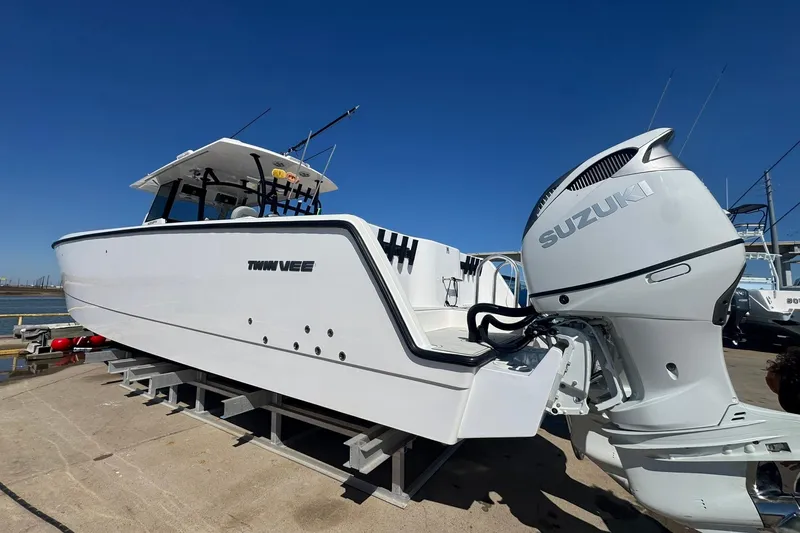 The Image of 2023 Twin Vee 400 GFX CC boat with Suzuki outboard engine on a dock. - 0