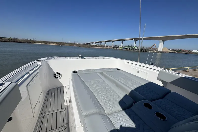 Slide: The Image of 2023 Twin Vee 400 GFX CC boat interior with seating, docked near a bridge. - 13