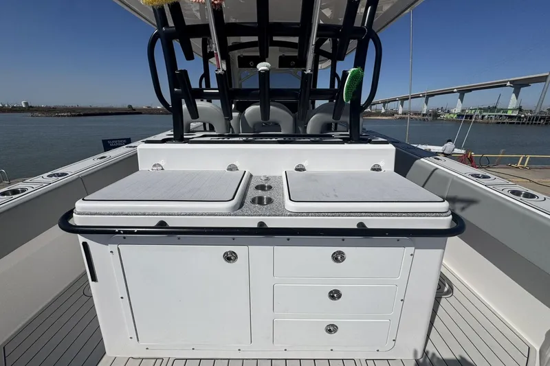 Slide: The Image of 2023 Twin Vee 400 GFX CC boat interior with seating and storage, docked by a bridge. - 15