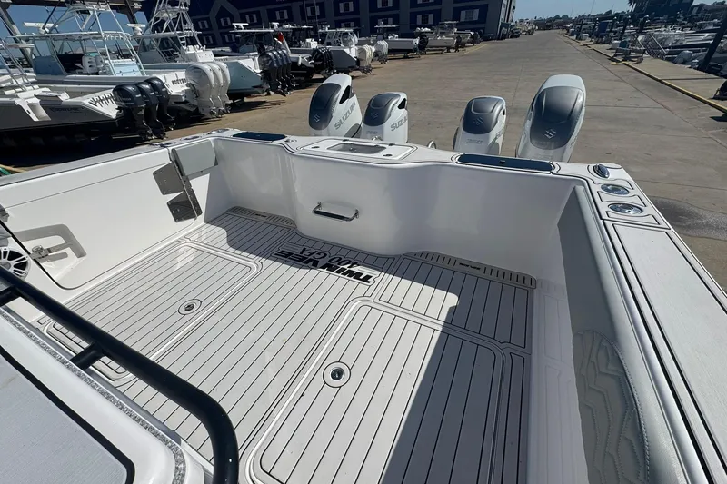 Slide: The Image of 2023 Twin Vee 400 GFX CC boat deck with Suzuki outboard engines at a marina. - 17