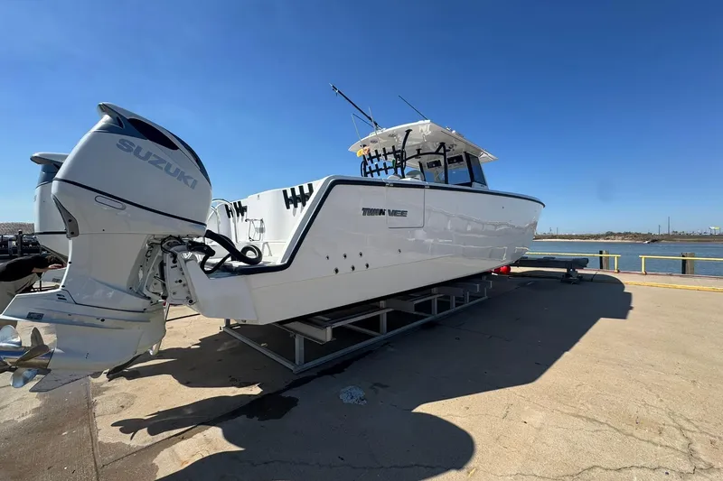 Slide: The Image of 2023 Twin Vee 400 GFX CC boat with Suzuki engines on a dock. - 2