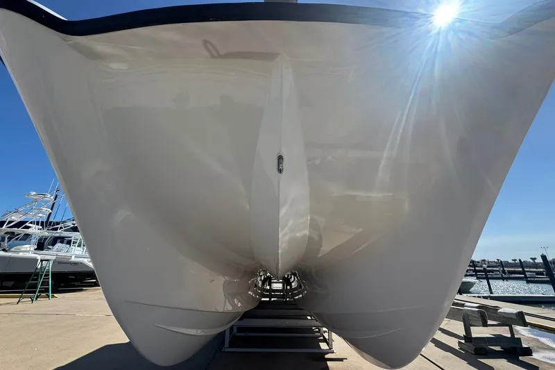 Slide: The Image of 2023 Twin Vee 400 GFX CC catamaran hull under bright sunlight at a marina. - 4
