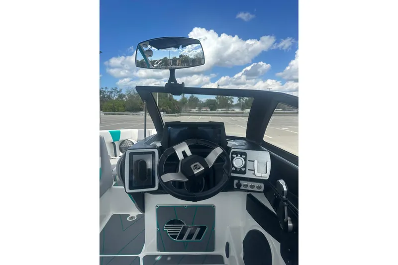 Slide: The Image of 2022 Malibu Wakesetter 23 LSV dashboard with steering wheel and controls under a blue sky. - 15