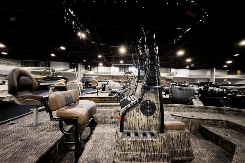 Slide: The Image of 2026 Excel 220 Bay Pro Elite boat interior at a showroom, featuring seating and controls. - 1