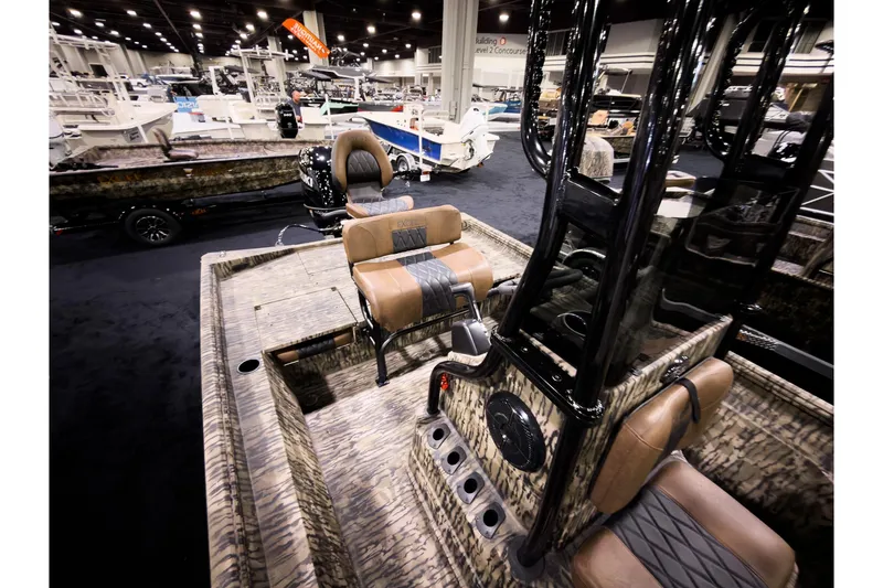Slide: The Image of 2026 Excel 220 Bay Pro Elite boat interior at a boat show, featuring camo design and seating. - 6